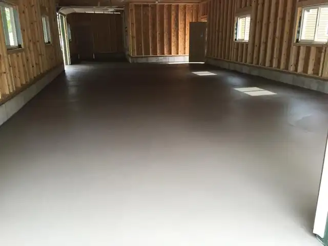 A smooth finished concrete floor inside a large timber-frame building