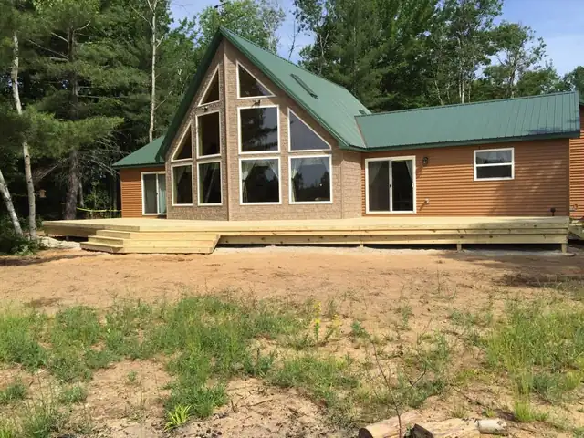 A-frame style new home with a green metal roof and a deck, built by JDC Construction