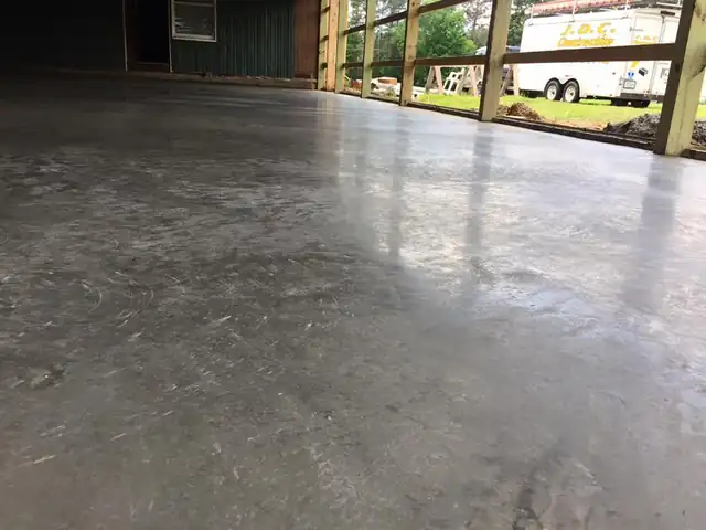 Large smooth concrete slab inside a pole building with a trailer parked outside