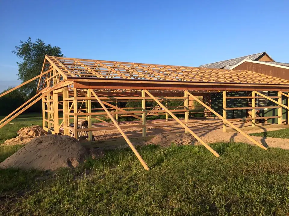 A pole building frame with roof sheathing going up on a JDC Construction job site