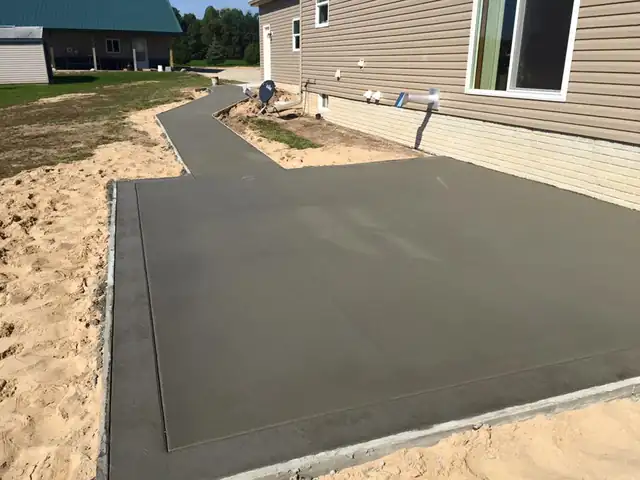 A poured concrete pad and walk beside a sided home, a JDC Construction job