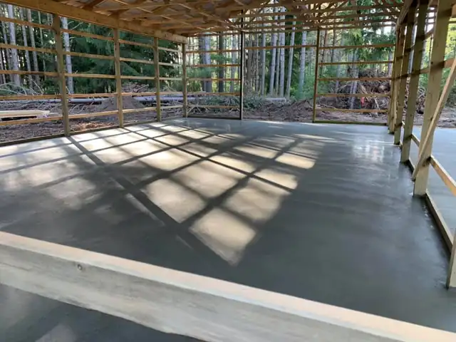 Concrete slab inside a pole building with sun patterns falling through the open frame