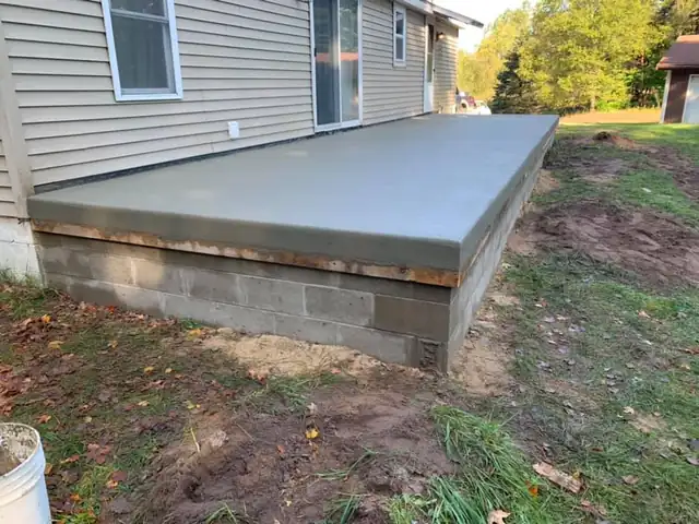 A newly poured porch or stoop slab on a block foundation base