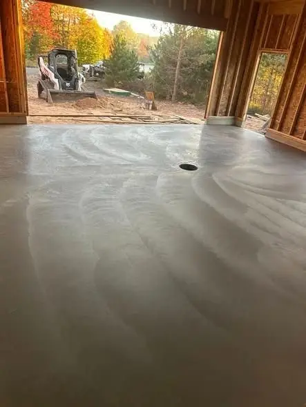 Looking out an open bay from inside a pole building onto the finished slab